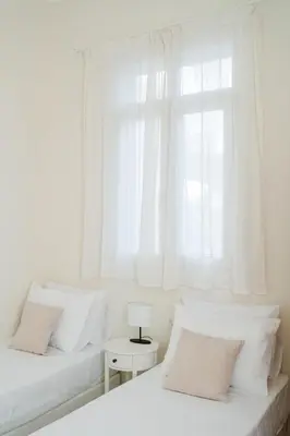 two beds in a white room with a window at Alcestis City Apartment in Rhodes Town
