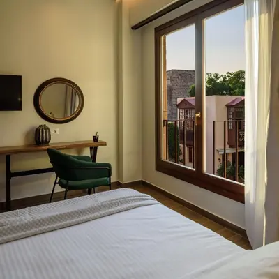 a bedroom with a bed and a desk and a window at Arthur Suites in Old Town in Rhodes Town