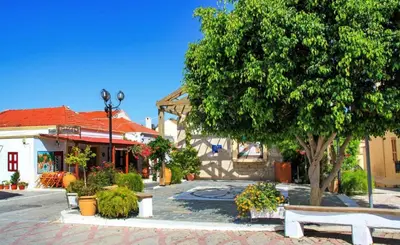 a park with benches and a tree and a building at M&K Traditional House in Theologos