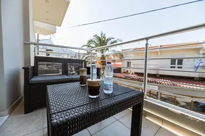 a table with two bottles of drinks on a balcony with a train at Archangelos SKY Junior Apartment in Archangelos