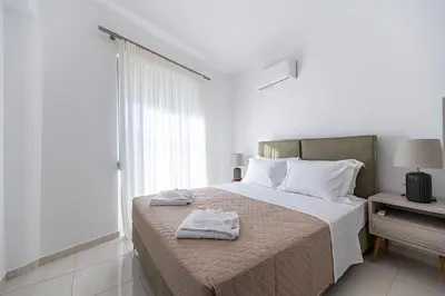 a white bedroom with a bed with towels on it at Archangelos SKY Junior Apartment in Archangelos