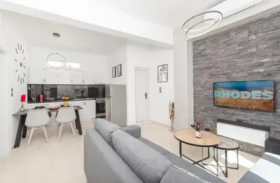 a living room with a gray couch and a brick wall at Casa di Hari in Afantou