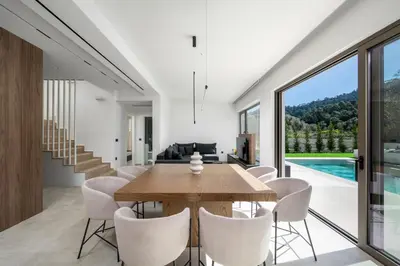a dining room with a wooden table and white chairs at Casa Yiava in Ialyssos