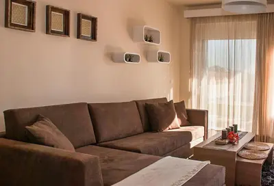 a living room with a brown couch and a window at Next to Haraki beach , taverns bars & 10 to Lindos in Haraki