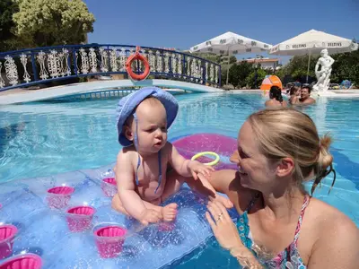 a woman and a baby in a pool at a resort at Aphrodite Apartments in Kallithea Rhodes