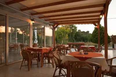 an outdoor restaurant with tables and chairs and windows at Aphrodite Apartments in Kallithea Rhodes