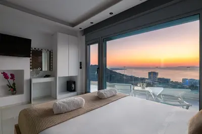 a bedroom with a large bed and a large window at Rhodes Skyline Suite with out Door Jacuzzi Sea View A2 in Ixia