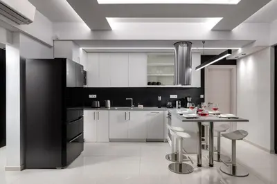 a kitchen with white cabinets and a table with stools at Rhodes Skyline Suite with out Door Jacuzzi Sea View A2 in Ixia