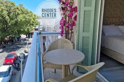 a balcony with a table and chairs and a bed at Golden City Center Suites in Rhodes Town