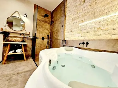 a bathroom with a bath tub and a mirror at Golden City Center Suites in Rhodes Town