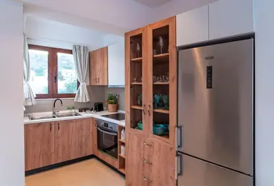 a kitchen with wooden cabinets and a stainless steel refrigerator at Kohili Suite Stegna Beach in Archangelos