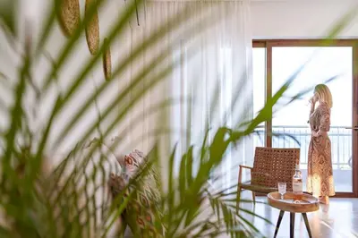 a woman standing in a room looking out of a window at Kohili Suite Stegna Beach in Archangelos
