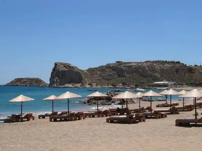 a beach with chairs and umbrellas on the sand at Kohili Suite Stegna Beach in Archangelos