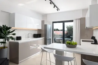 a kitchen with white cabinets and a table with a bowl of fruit at K Luxury Apartment in Rhodes Town