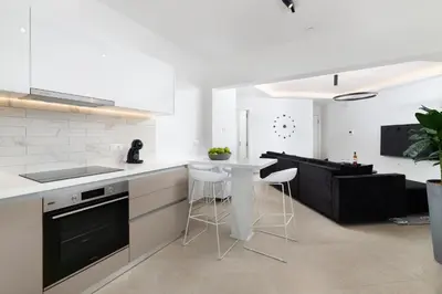 a white kitchen with a counter and stools at K Luxury Apartment in Rhodes Town