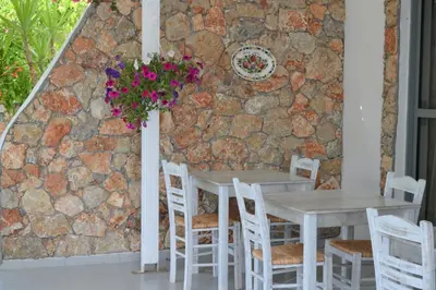 two tables and chairs in front of a stone wall at Hotel Irini in Livadia