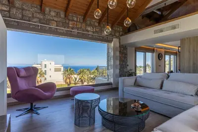 a living room with a couch and a large window at Rhode Luxury Villa in Kalithies