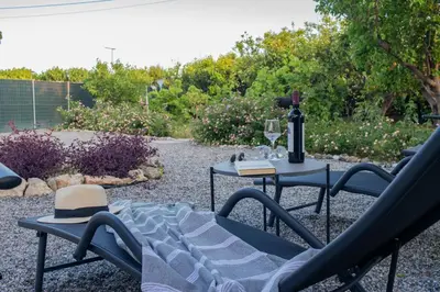 a patio with a table and two chairs and a bottle of wine at Beachside Apartment-2 in Afantou