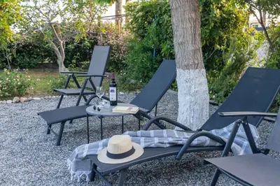 two chairs with a hat and a table with a bottle of wine at Beachside Apartment-2 in Afantou