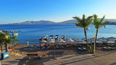 a beach with umbrellas and people sitting on the beach at Sirin Luxury Suites - 1st floor in Haraki