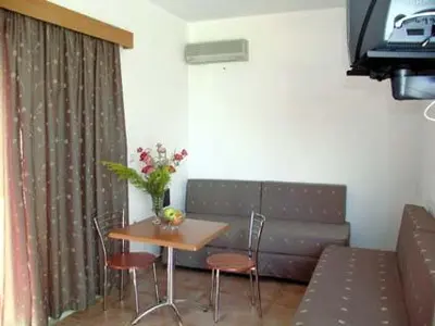 a living room with a couch and a table and chairs at Lakis Apartments in Faliraki