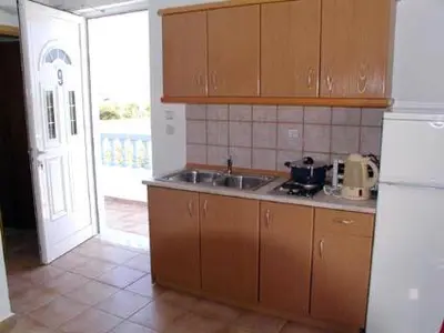 a kitchen with a sink and a door to a patio at Lakis Apartments in Faliraki