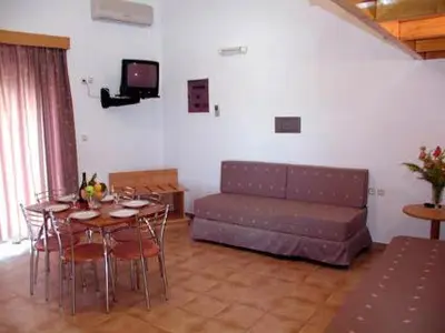a living room with a couch and a table and chairs at Lakis Apartments in Faliraki