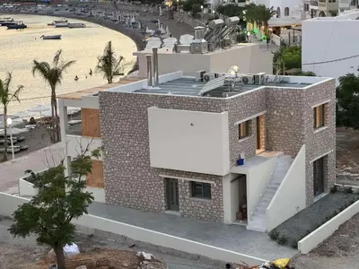 a building on the beach with a white sign on it at Sirin Luxury Suites Groundfloor in Haraki