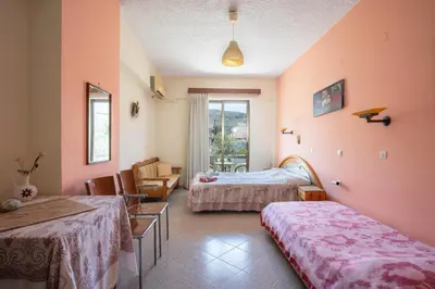 a room with two beds and a chair and a window at Cozy Archangelos apartments with private parking in Archangelos
