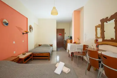 a room with two beds and a dining room with a table at Cozy Archangelos apartments with private parking in Archangelos