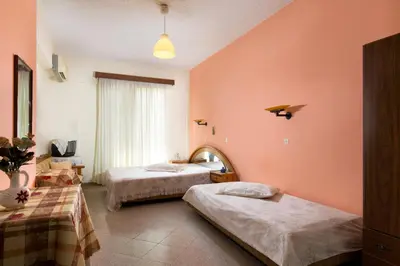 two beds in a room with pink walls at Cozy Archangelos apartments with private parking in Archangelos