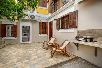 a patio with two chairs and a table and a stove at Lemon Tree Symi in Symi