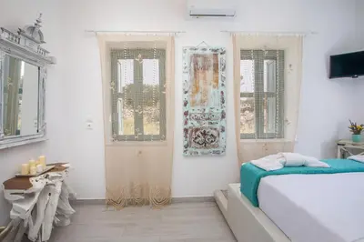 a bedroom with a bed and two windows and a door at Lady Stamatias House in Halki