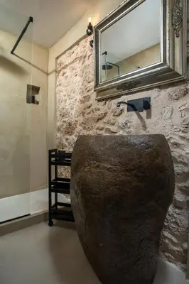 a bathroom with a mirror and a stone wall at Lady Stamatias House in Halki