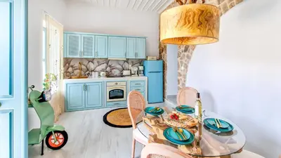 a kitchen with blue cabinets and a table and a scooter at Lady Stamatias House in Halki