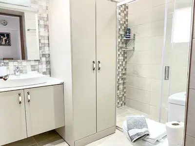 a white bathroom with a shower and a sink at La Casa di villagio in Koskinou