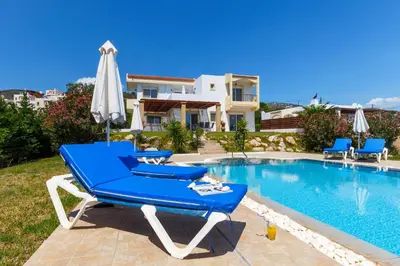 a blue lounge chair and an umbrella next to a swimming pool at Villa Alexi in Kalathos