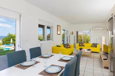 a dining room and living room with a table and chairs at Villa Alexi in Kalathos