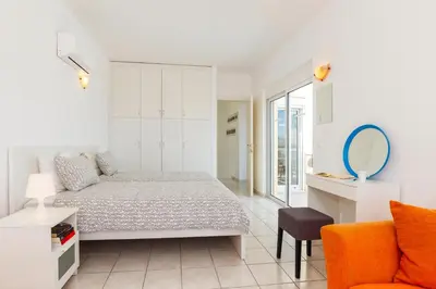 a white bedroom with a bed and a chair at Villa Alexi in Kalathos