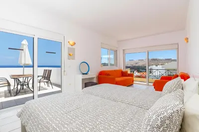 a white bedroom with a bed and a balcony at Villa Alexi in Kalathos