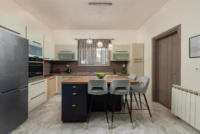 a kitchen with a large island with stools and a table at Christos House in Afantou