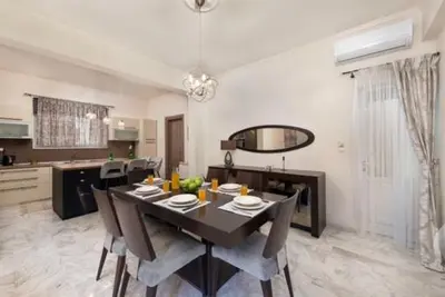 a dining room with a table and chairs and a kitchen at Christos House in Afantou