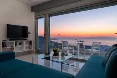 a living room with a blue couch and a glass table at Rhodes SkyLine Suite with out Door Jacuzzi Sea View A1 in Ixia