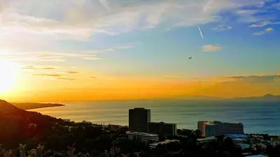a sunset over the ocean with a city at Rhodes SkyLine Suite with out Door Jacuzzi Sea View A1 in Ixia