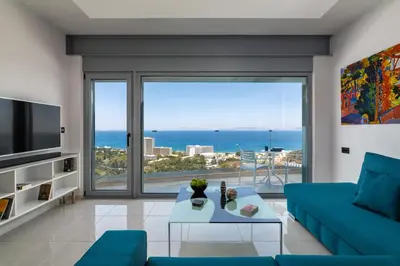a living room with a blue couch and a large window at Rhodes SkyLine Suite with out Door Jacuzzi Sea View A1 in Ixia