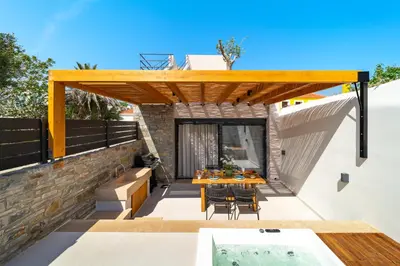 a patio with a wooden pergola and a table and chairs at Atria luxury experience in Kattavía