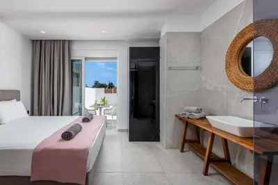 a bedroom with a bed and a sink and a tub at JOHANNES LUXURY VILLAS in Kolimbia