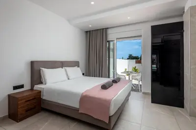 a bedroom with a large bed and a balcony at JOHANNES LUXURY VILLAS in Kolimbia