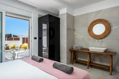 a bedroom with a bed and a sink and a mirror at JOHANNES LUXURY VILLAS in Kolimbia