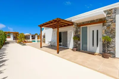 a patio of a house with a stone wall at JOHANNES LUXURY VILLAS in Kolimbia